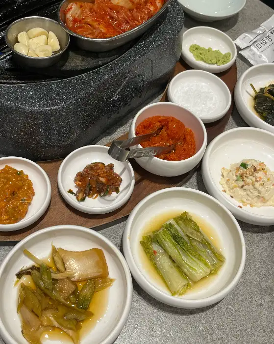 다양한 종류의 밑반찬이 여러 개의 작은 접시에 담겨 나옵니다. 신선한 재료와 정갈한 플레이팅이 돋보입니다.