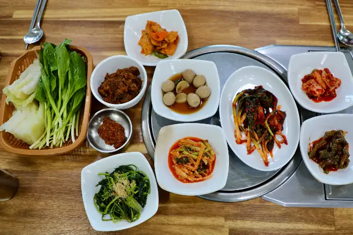 여러가지 밑반찬과 쌈채소가 차려진 테이블 모습