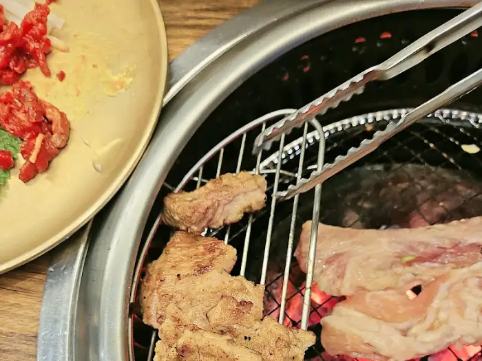 집게로 집어 그릴 위에서 익어가는 돼지갈비 조각