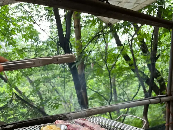 산속 풍경을 배경으로 숯불에 고기를 굽는 모습