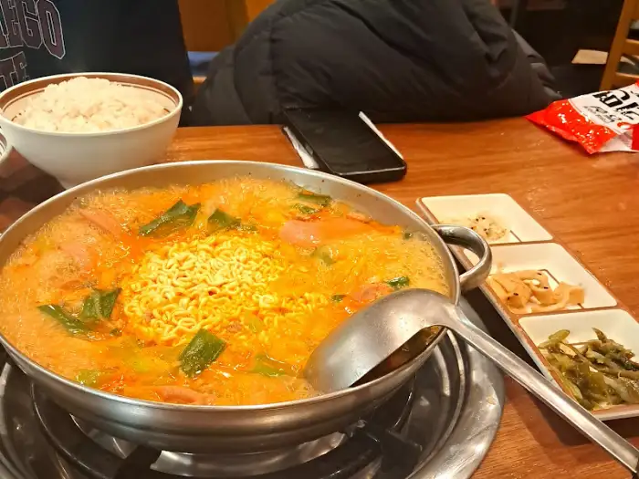 부대찌개 냄비와 밥, 반찬이 함께 놓인 전체적인 테이블 모습