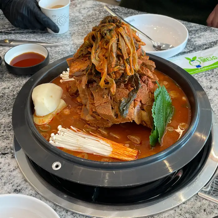 감자탕 냄비에 묵은지와 뼈다귀, 팽이버섯, 알수제비가 올려져 있는 모습