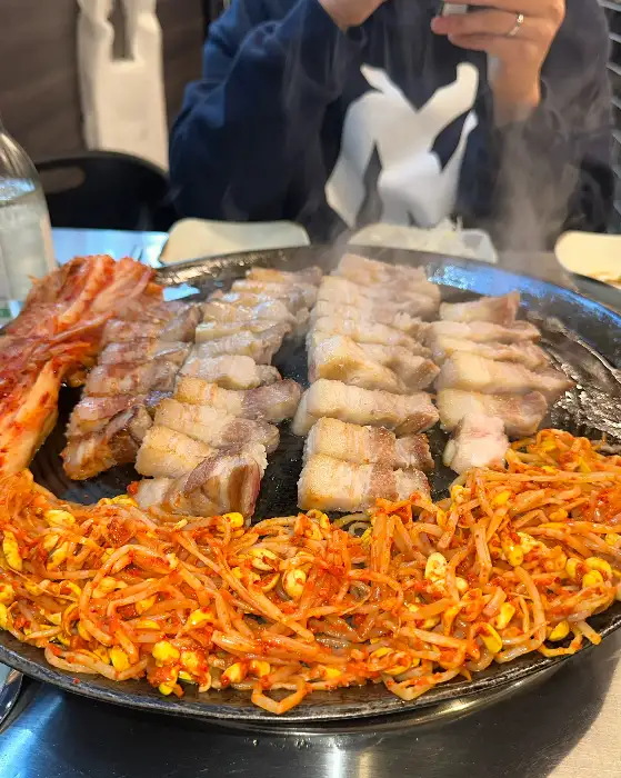 솥뚜껑 위 삼겹살이 익어가며 김이 나는 모습
