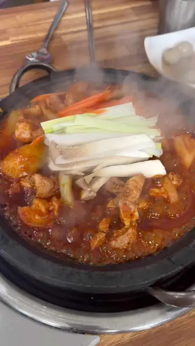 돌판 위에서 익어가는 돼지두루치기에 야채와 버섯이 더해지는 모습