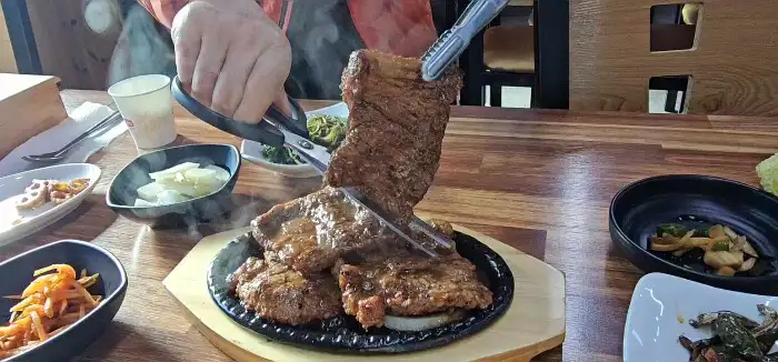 집게로 집어 올린 먹음직스러운 돼지갈비