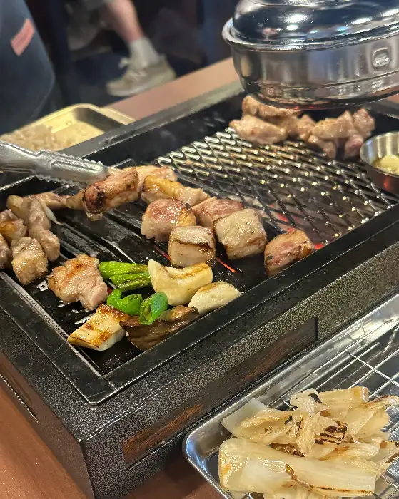 숯불 위에서 익어가는 고기와 곁들임 채소