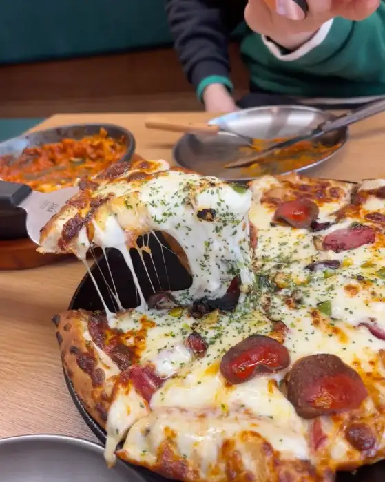 피자 조각을 자르는 손과 흘러내리는 치즈