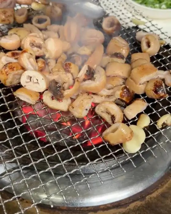 숯불 위에서 익어가는 막창과 곁들임 음식