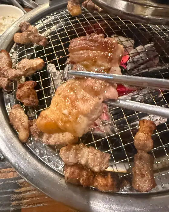 집게로 집어 올린 두툼한 삼겹살 조각