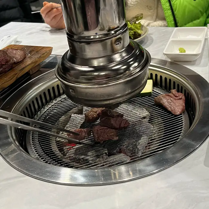 집게로 숯불 위의 고기를 뒤집는 모습