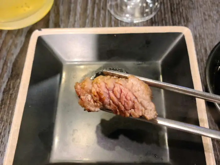 집게로 집어 올린 부드러운 우대갈비 조각