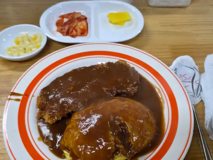 돈까스, 오므라이스, 떡만두국 세트가 담긴 접시와 반찬