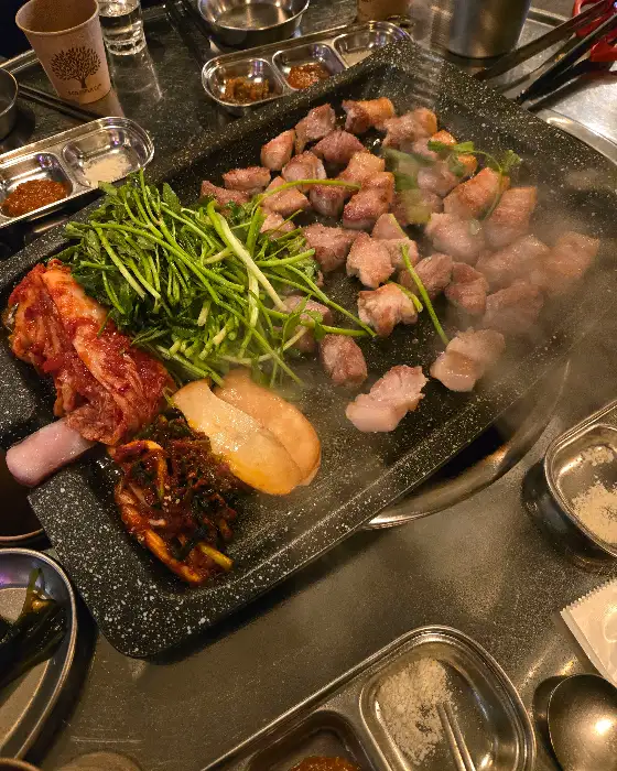 철판 위에서 구워지는 삼겹살과 목살, 그리고 미나리