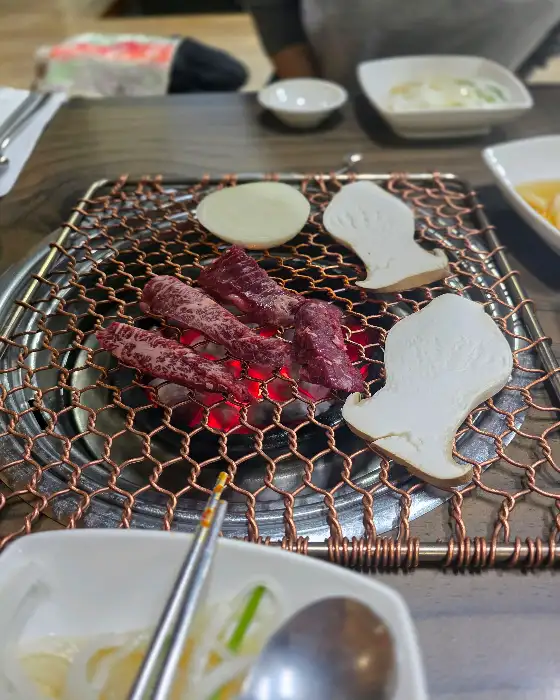 숯불 위에서 맛있게 구워지고 있는 소고기. 버섯도 함께 올라가 있습니다.