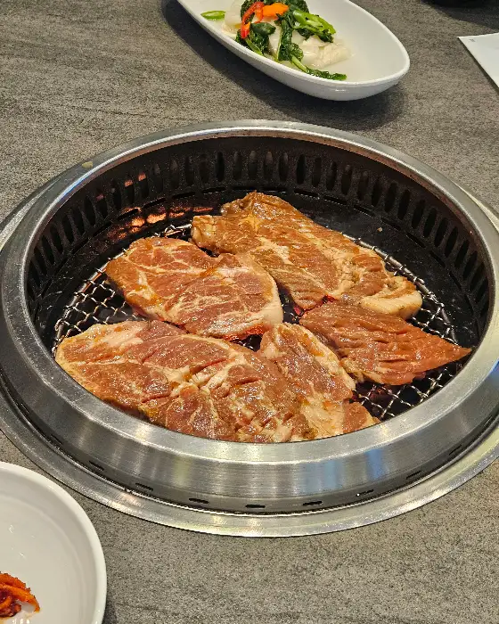 숯불 위에서 구워지고 있는 두툼한 고기 여러 점
