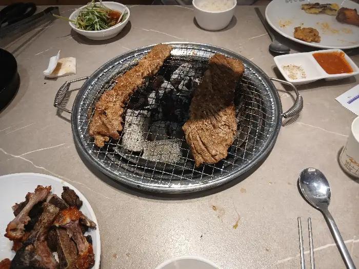 숯불 위에서 익고 있는 다양한 갈비 조각들