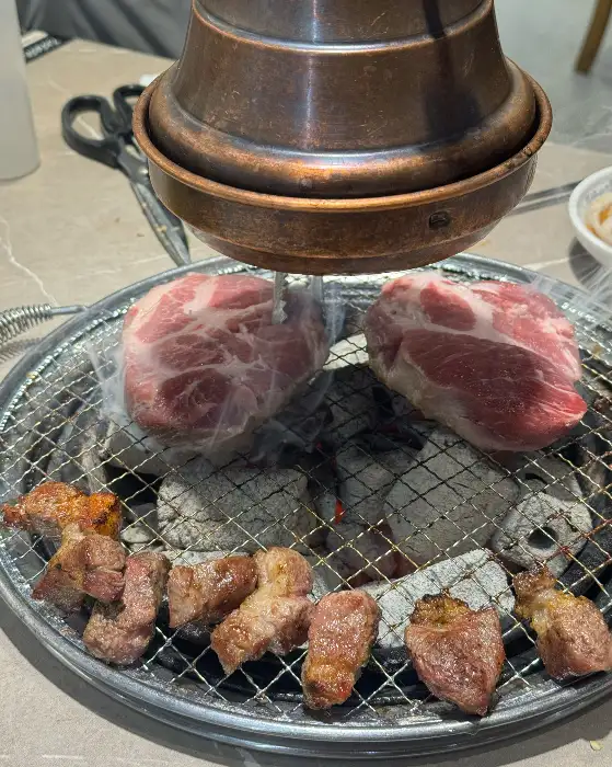 숯불 위에서 익고 있는 두툼한 고기 덩어리