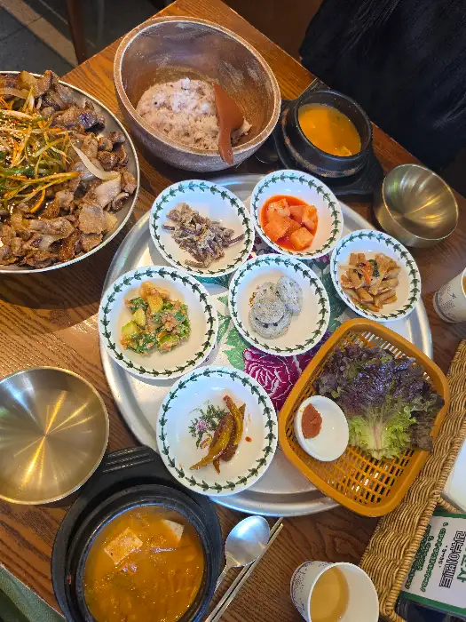 메인 요리인 청국장, 불백, 그리고 여러 반찬들이 놋그릇에 담겨 나온 모습.