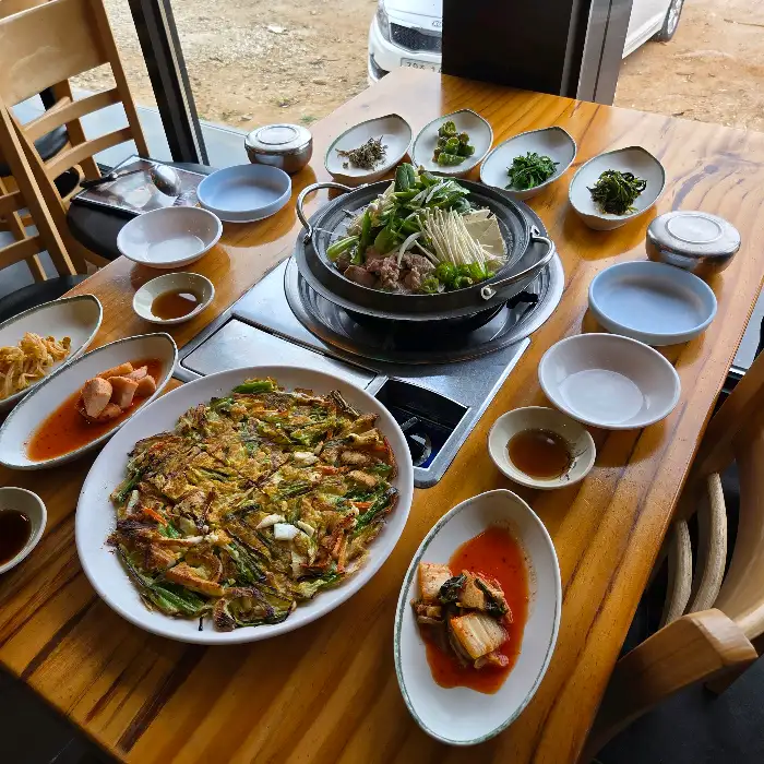 테이블 가득 차려진 젓국갈비전골과 각종 반찬들의 모습
