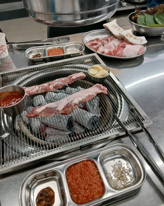 숯불 위에서 구워지는 고기와 곁들임 반찬