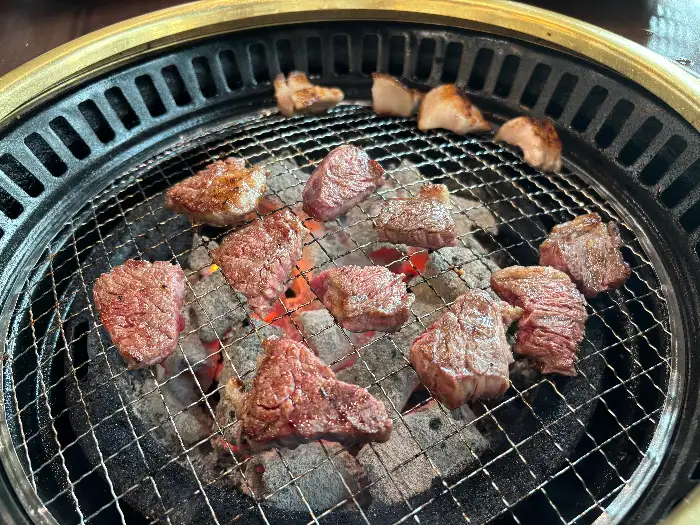 다양한 크기와 모양의 소고기 조각들이 숯불 위에서 익고 있는 모습