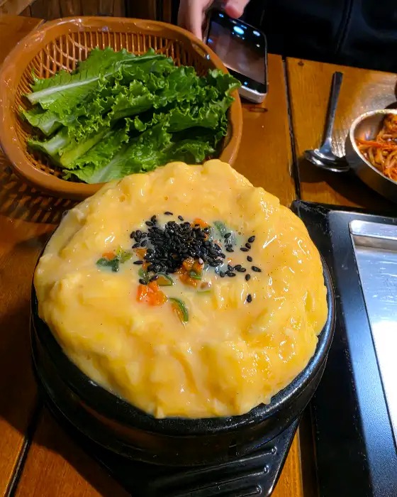 푸짐하게 부풀어 오른 계란찜 위에 검은깨가 뿌려져 있는 모습