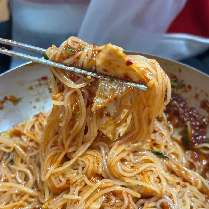 젓가락으로 비빔밀면을 집어 올리는 모습