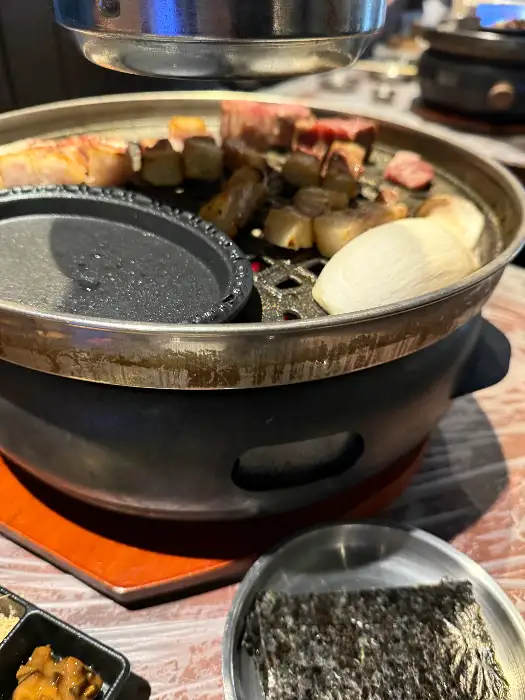 잘 익어가는 고기와 함께 에링기 버섯, 마늘 등이 불판에 함께 구워지고 있는 모습.