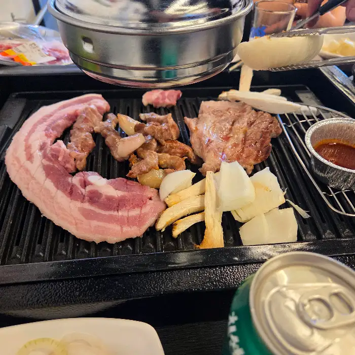 잘 구워지고 있는 고기와 곁들임 메뉴, 소주와 맥주병