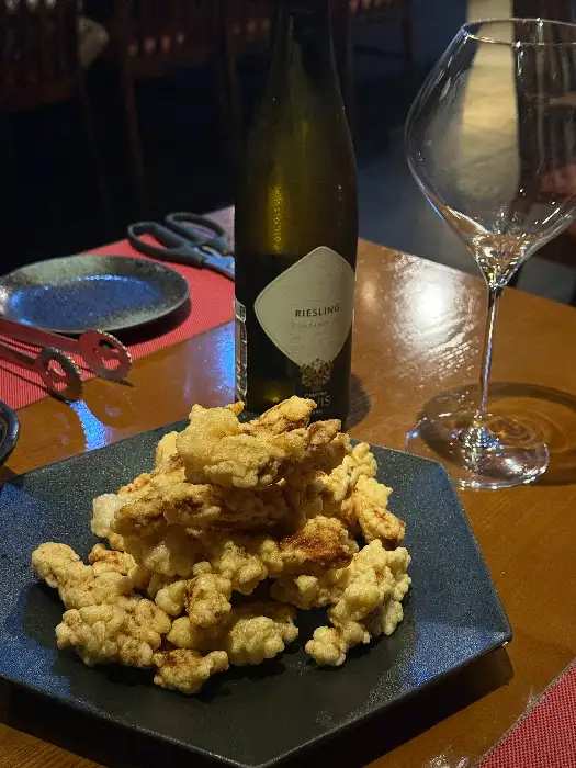 바삭한 탕수육 조각들이 접시에 담겨 있고, 옆에는 와인잔과 소스가 있습니다.