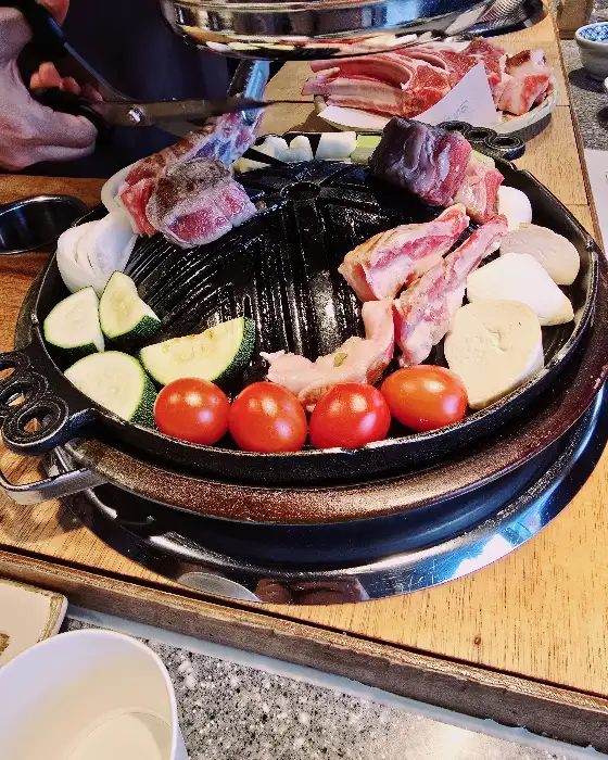 직원분이 양갈비를 불판 위에서 맛있게 굽고 있는 모습
