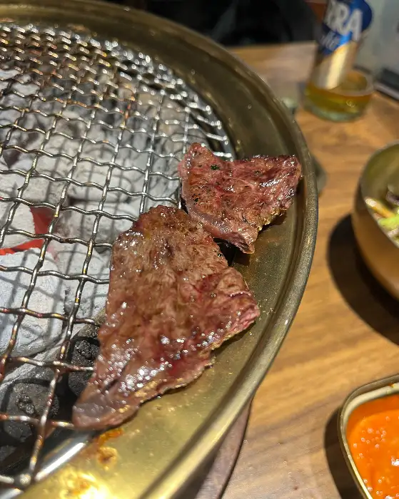 구워진 소고기 조각이 숯불 위에서 지글거리는 모습