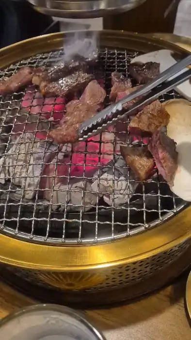 집게로 숯불 위 소고기를 뒤집는 모습