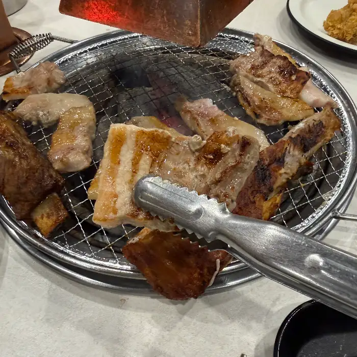 숯불 위에 구워지고 있는 다양한 부위의 돼지고기