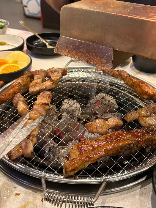 숯불 위에서 맛있게 구워지고 있는 갈비와 다른 고기들