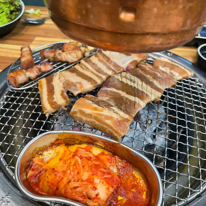 불판 위에 올라간 삼겹살과 곁들임 김치