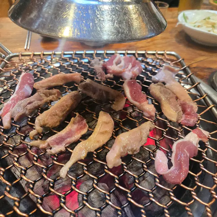 숯불 위에서 구워지고 있는 다양한 부위의 오리고기