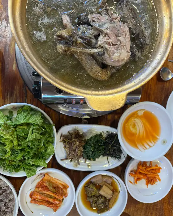 오리백숙이 담긴 냄비와 여러 가지 반찬들