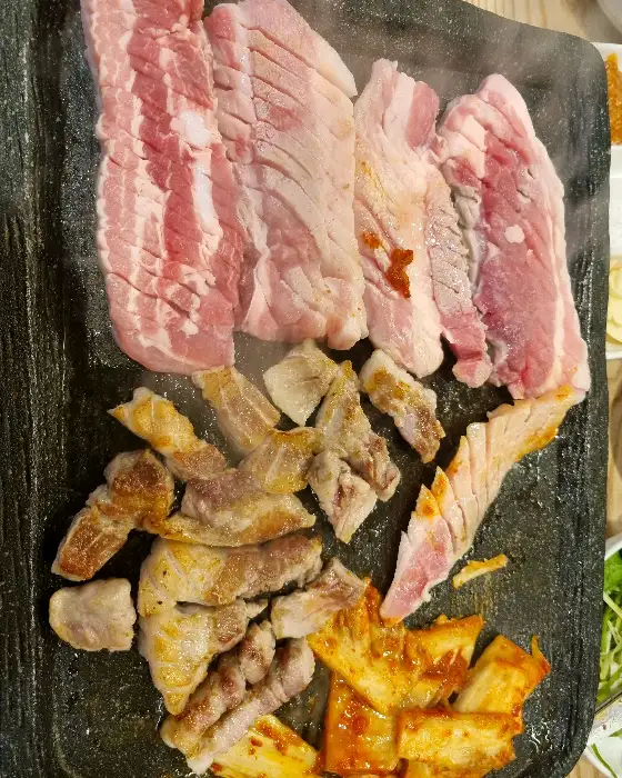 돌판 위에 구워지고 있는 삼겹살과 김치