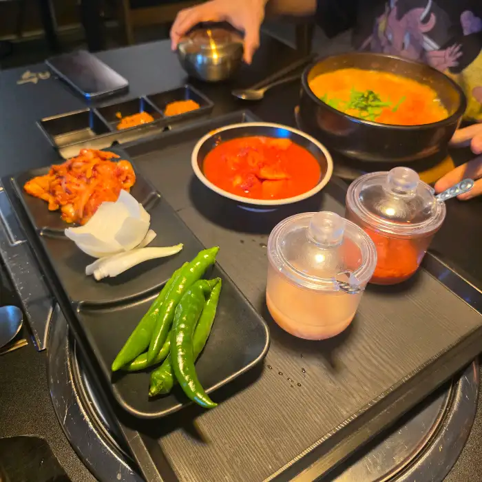 식탁 위에 놓인 국밥, 반찬, 소스 용기들.