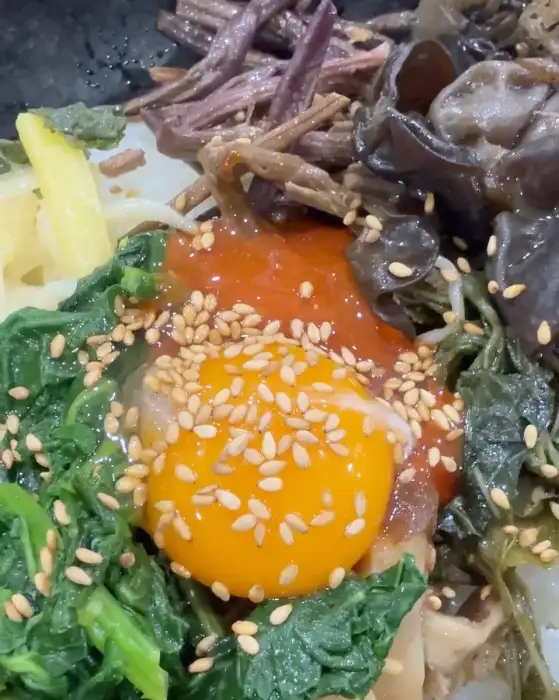 비빔밥 위에 계란 노른자와 각종 나물이 올라간 모습