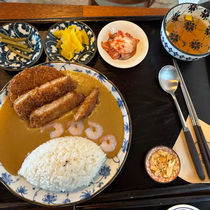 카레라이스와 가라아게, 새우튀김, 소세지 토핑이 풍성하게 올라간 모습. 곁들임 반찬도 정갈하다.