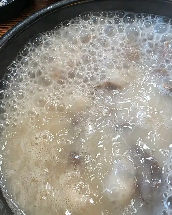 뽀얀 국물 위로 떠다니는 거품과 고기