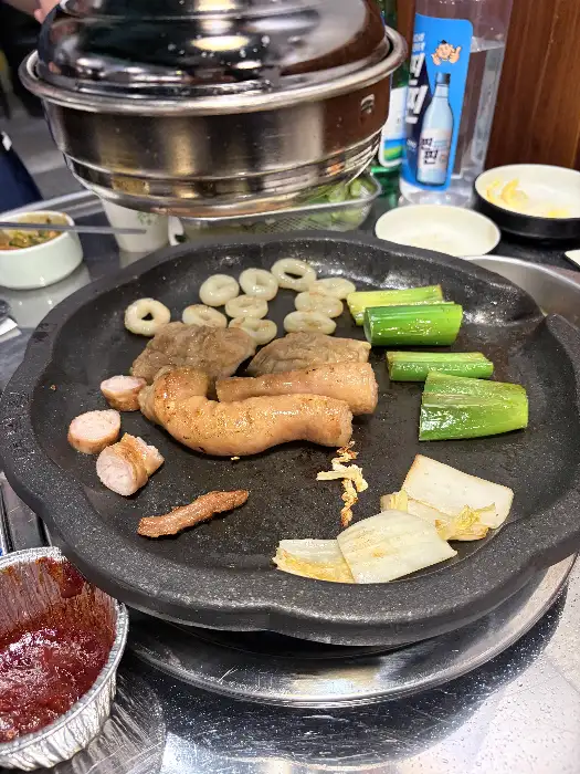 돌판 위에 올려진 막창과 곁들임 채소의 클로즈업
