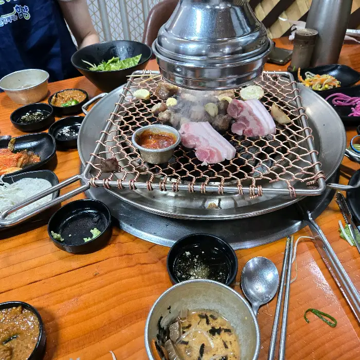 화로 위에서 구워지는 고기와 곁들임 음식들