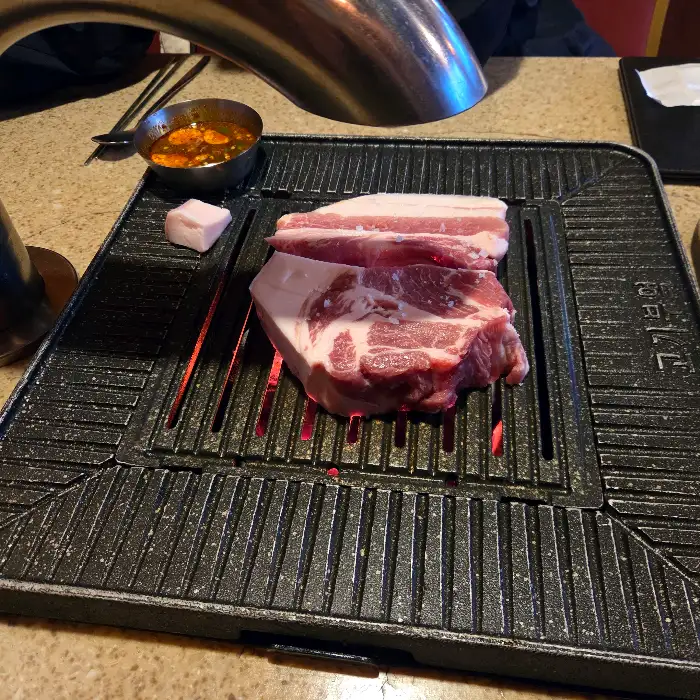 불판 위에서 익어가는 두툼한 흑돼지 목살