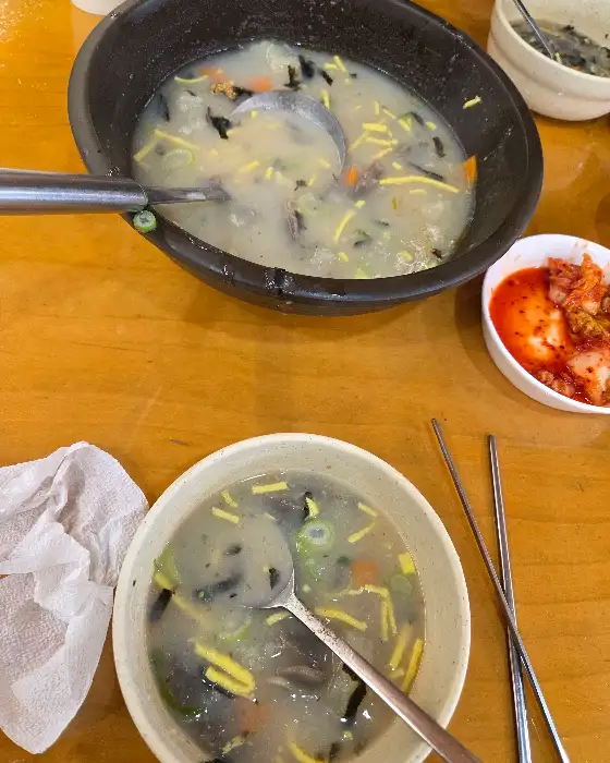 따뜻한 옹심이 국물이 담긴 뚝배기와 그릇이 보입니다.
