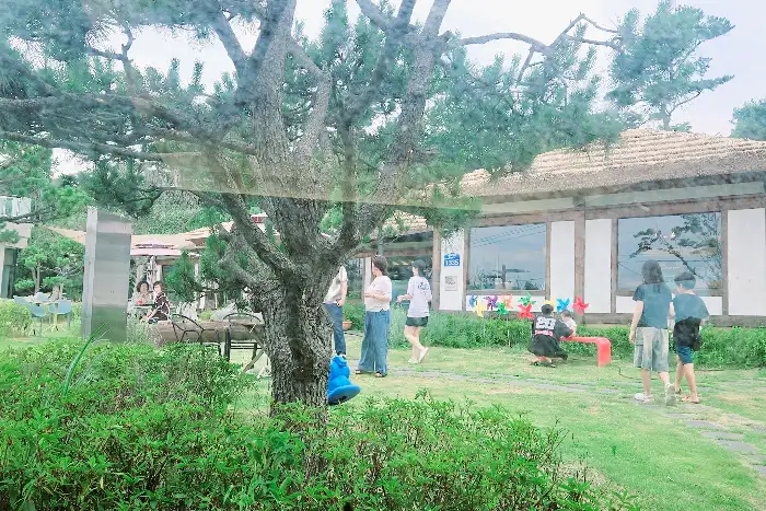 구유림 야외에서 바라본 카페 건물과 정원 - 여러 사람이 정원을 즐기고 있는 모습