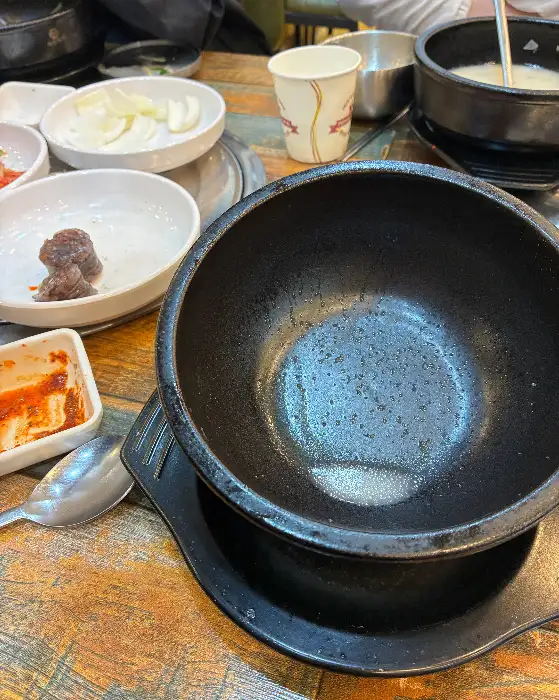 빈 뚝배기와 덜어먹고 남은 반찬들이 놓인 테이블 모습, 깔끔한 식사를 마친 후의 풍경입니다.