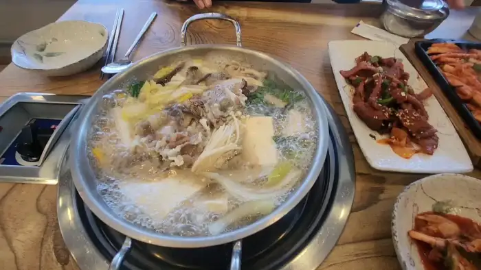 식탁 위에서 끓고 있는 전골과 옆에 놓인 더덕구이, 파전 등의 모습
